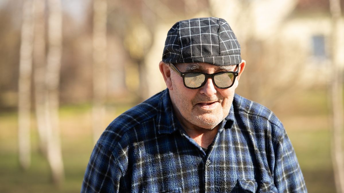 Una persona mayor con gorra y gafas. Persona sin hogar